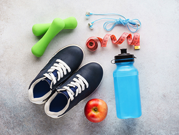 Dumbbells, headphones, measuring tap, running shoes, apple and water bottle.