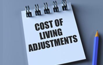 Spiral-bound notepad on a desk displaying the words “Cost of Living Adjustments,” with a pencil placed beside it.